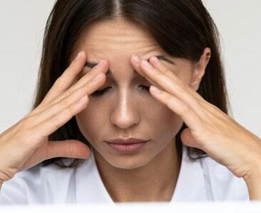 Woman rubbing her forehead because of a headache or migraine